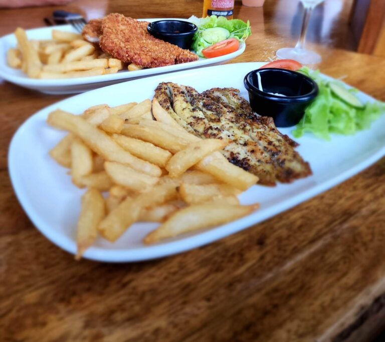 Plates of Barramundi, chicken schnitzel salad and chips at the Daintree Siesta restaurant