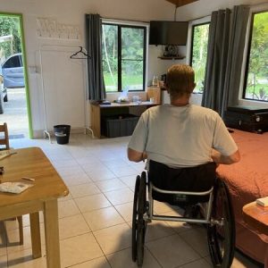 man in a wheelchair in a spacious motel room.