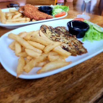 Plates of Barramundi, chicken schnitzel salad and chips at the Daintree Siesta restaurant